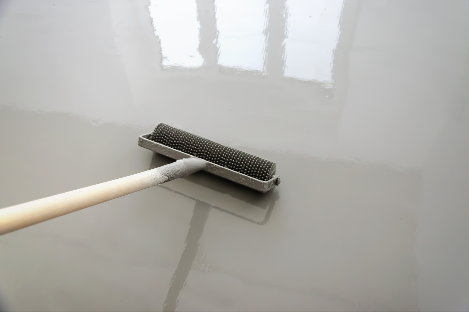 Close-up of a spiked roller used to apply and level a fresh epoxy or polyaspartic floor coating.