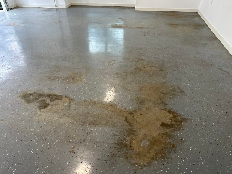 Damaged and worn epoxy garage floor with extensive peeling and stained areas.