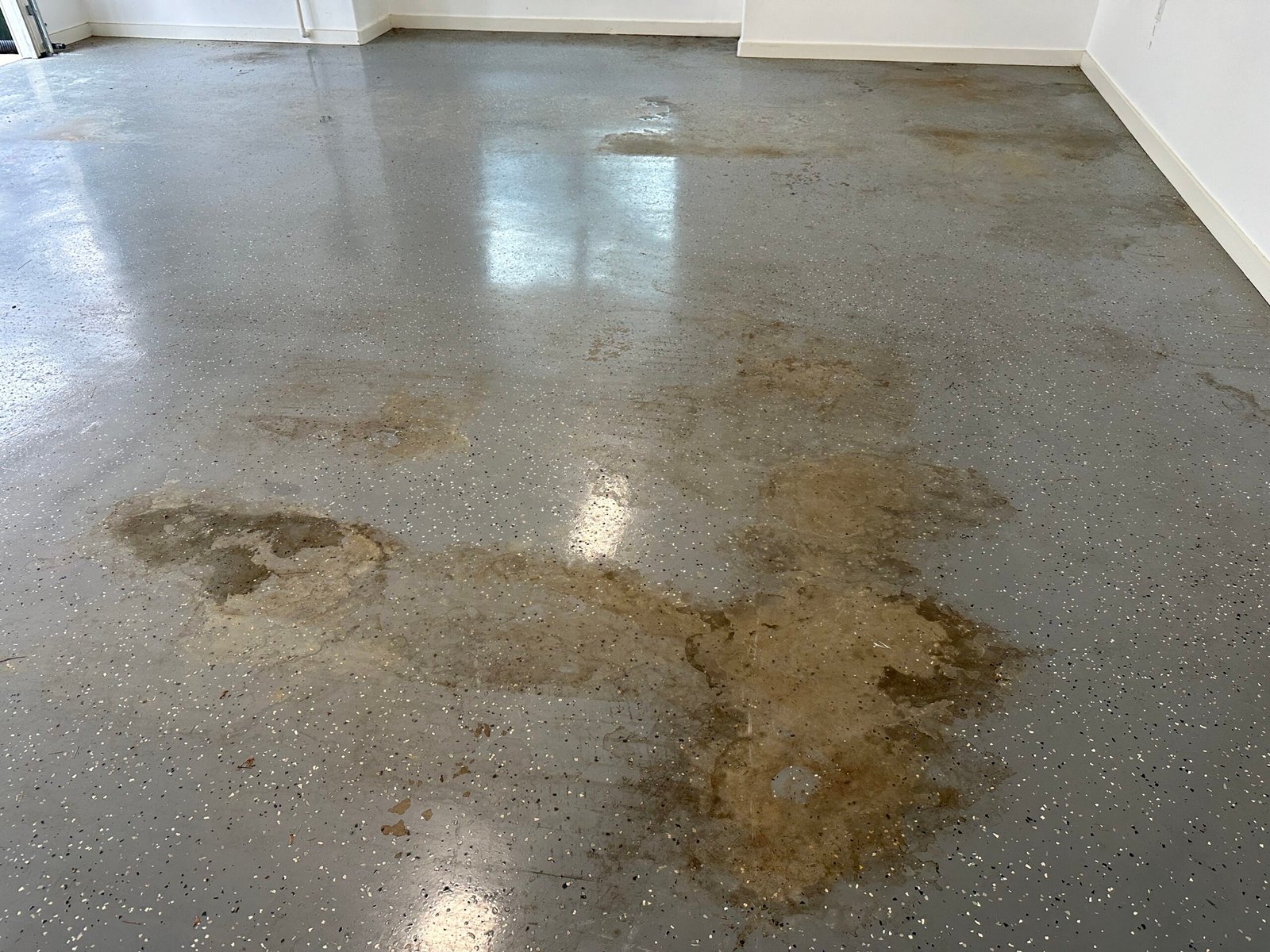 Damaged and worn epoxy garage floor with extensive peeling and stained areas.