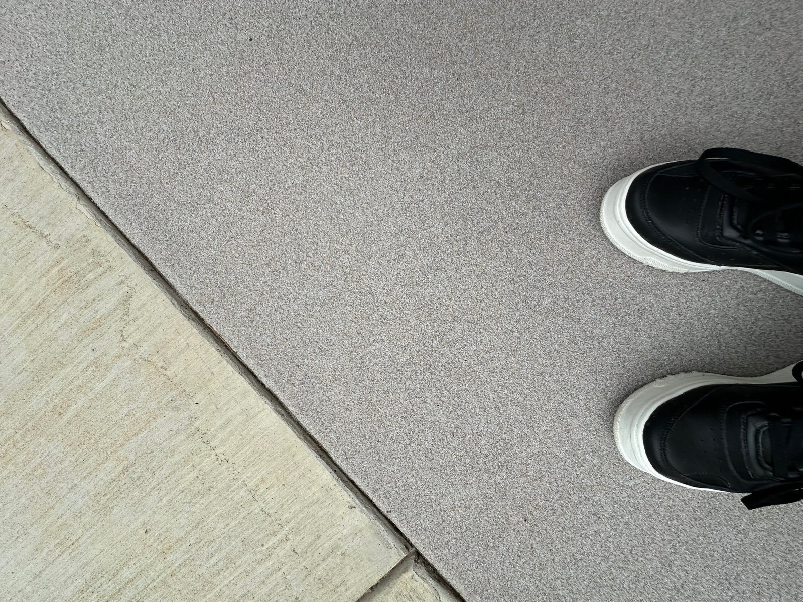 Close-up of Oyster quartz floor next to concrete with shoes for scale