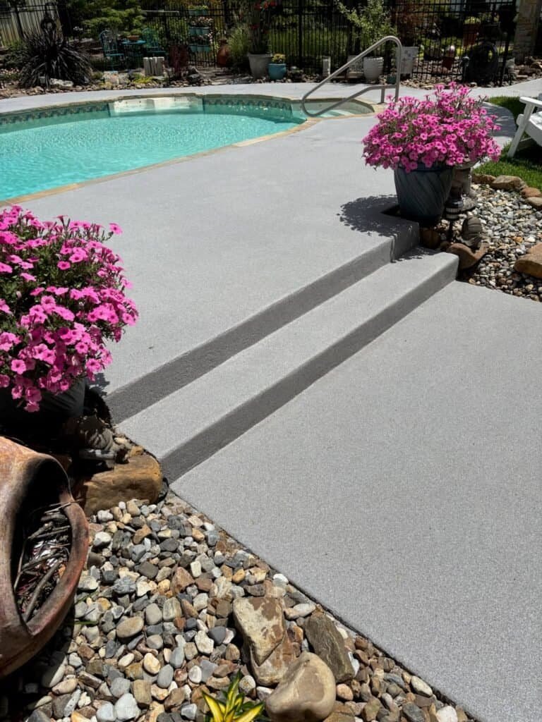 Quartz-broadcast outdoor pool deck coating with textured light-gray finish on steps