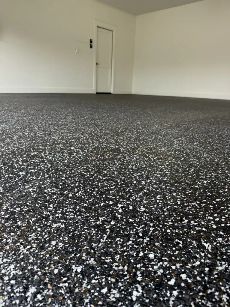 Bright black and white epoxy coating on residential garage floor with smooth, durable finish.