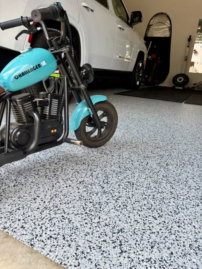 Bright blue mini motorcycle on epoxy coated garage floor with white and black speckled finish.