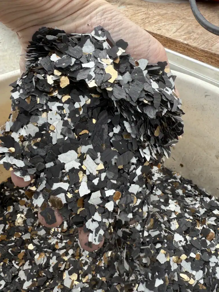 Vibrant black and gold epoxy flake mix for concrete flooring, durable and decorative epoxy resin coating.