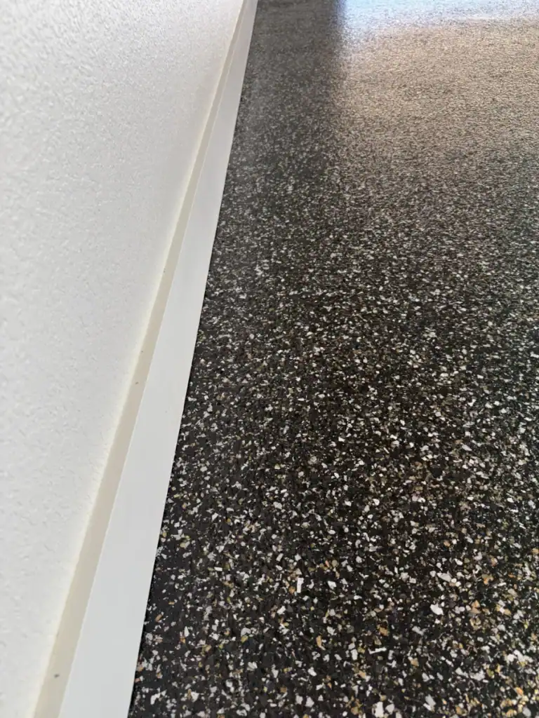 Durable epoxy floor coating with speckled black and white finish for commercial or industrial spaces.