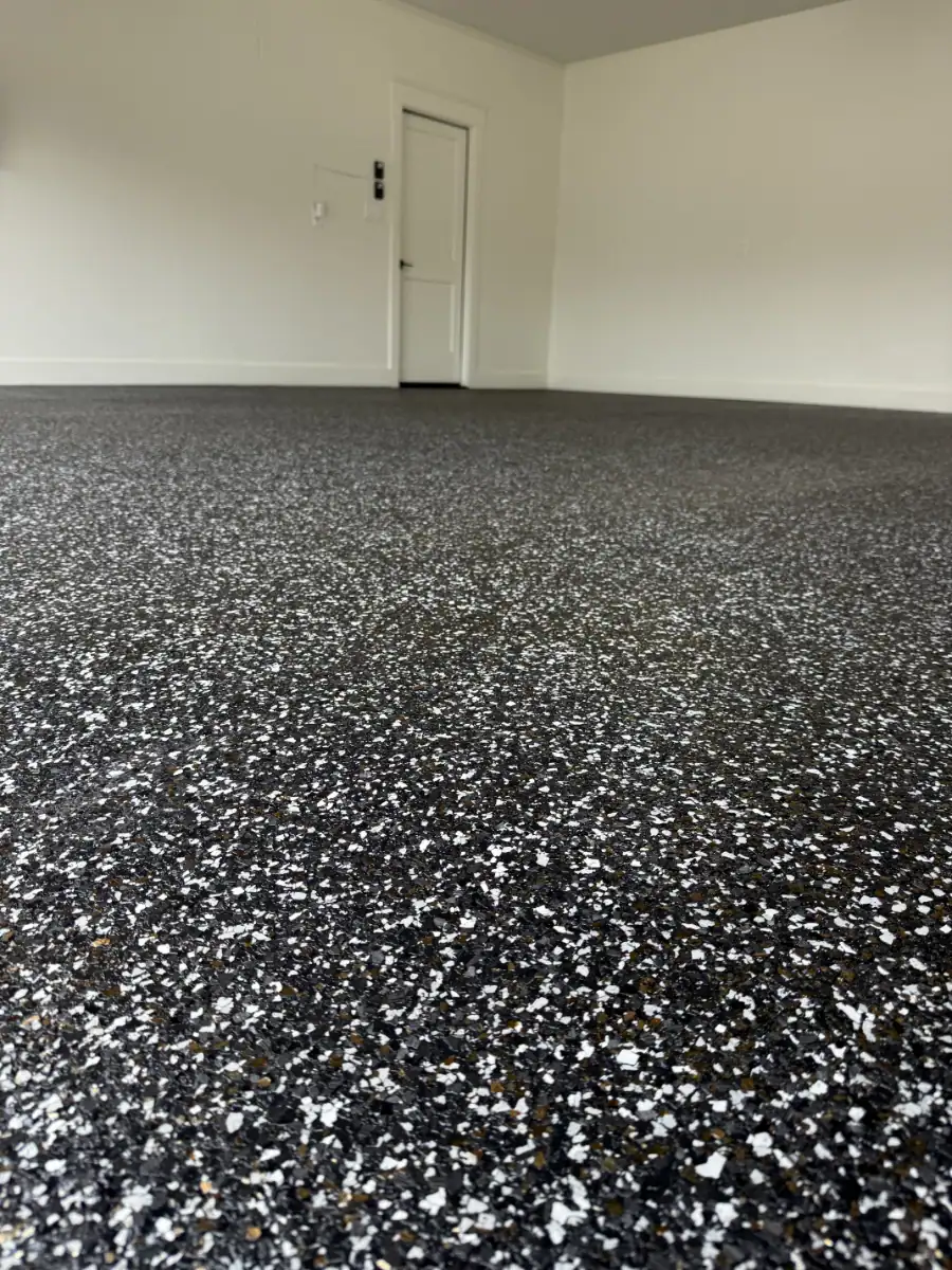 Vibrant black and white epoxy floor coating with gold metallic flakes in a modern interior space.