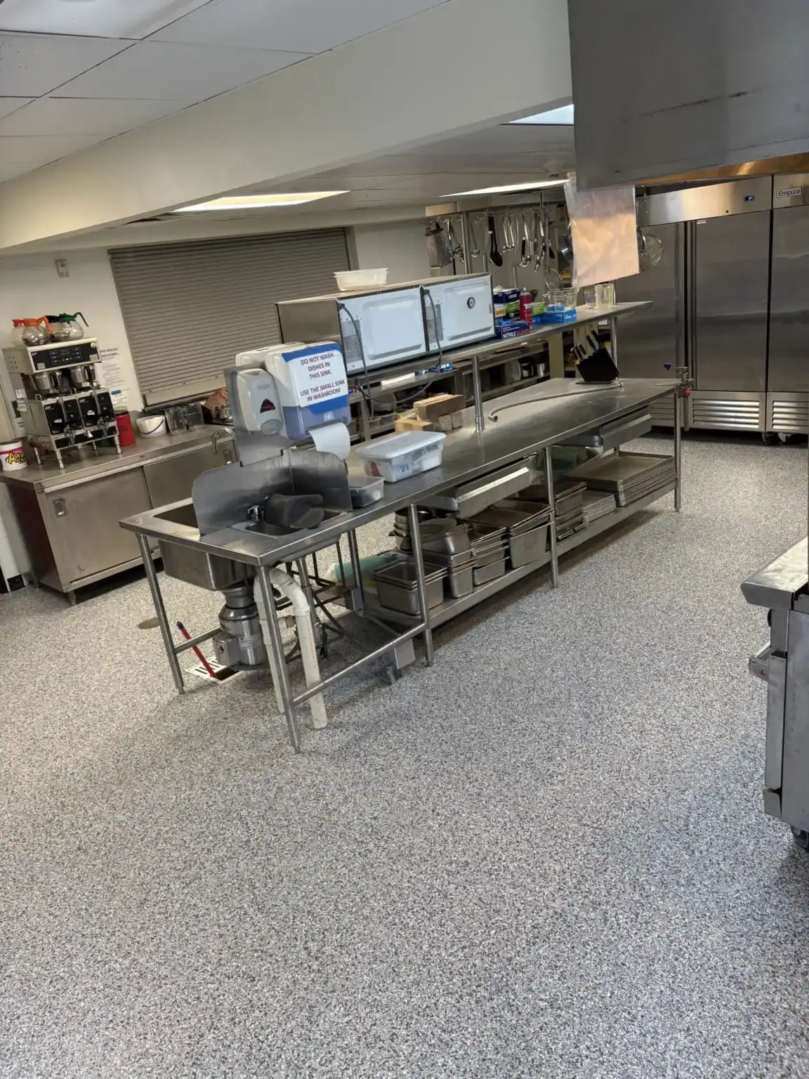 Commercial kitchen with stainless steel workstations and equipment.