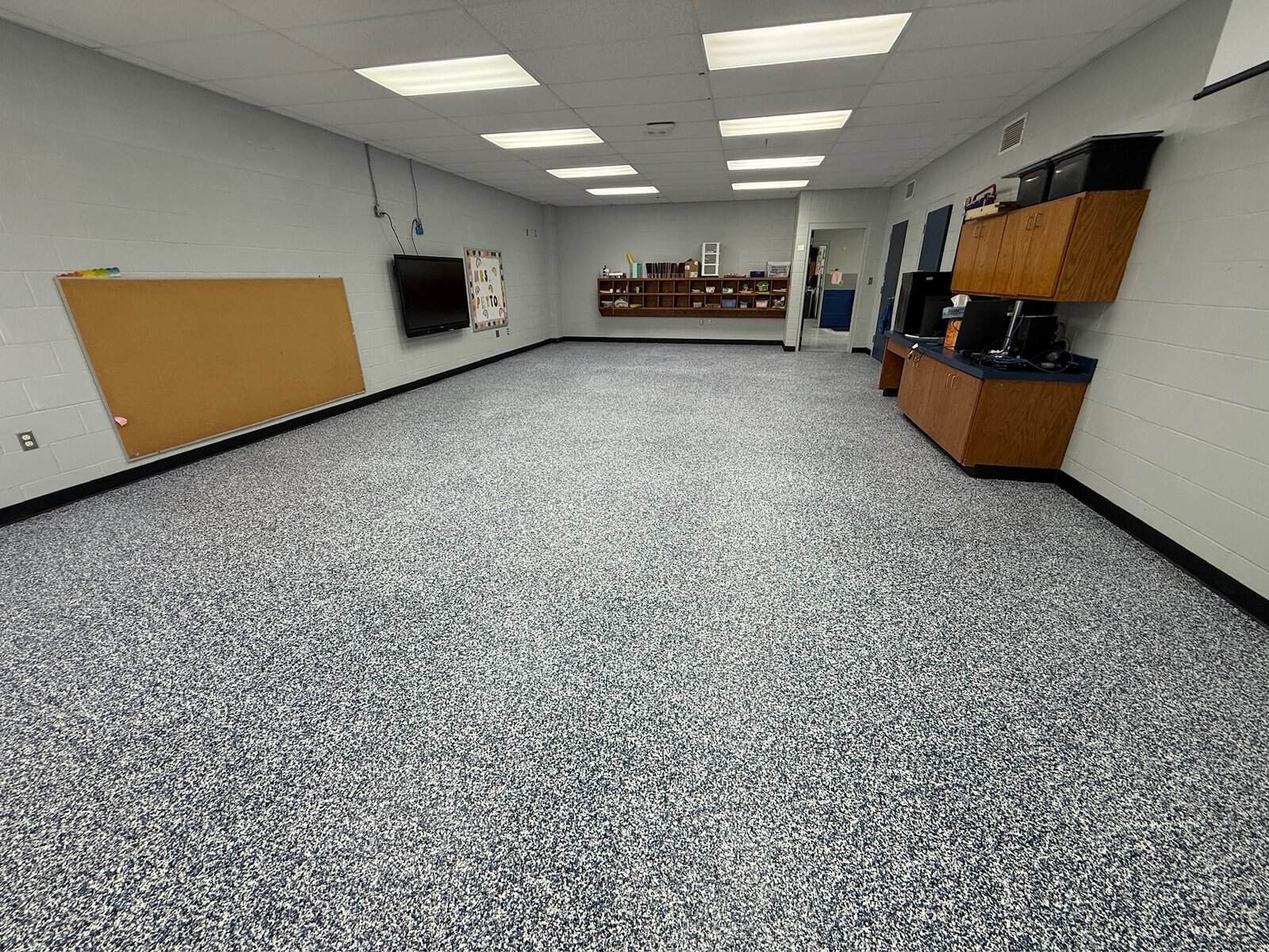 Interior of a commercial room with epoxy-coated floor and wall-mounted TV.