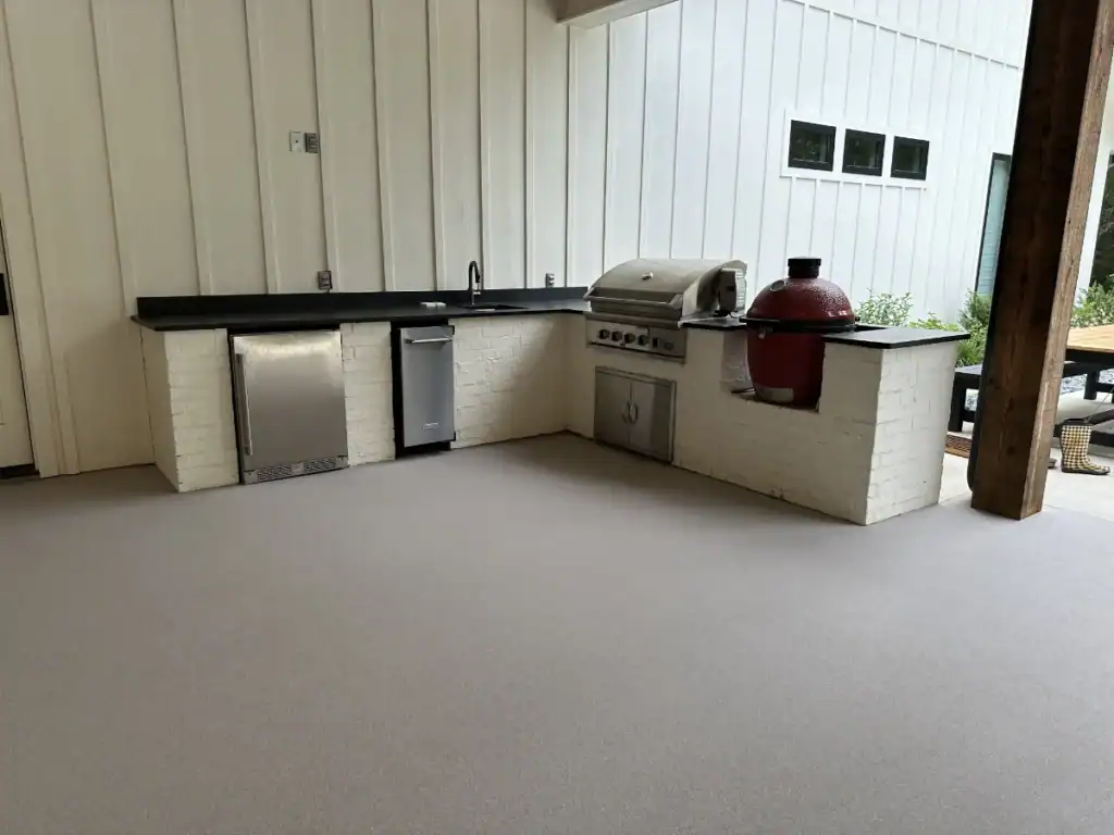 Outdoor kitchen with epoxy-coated flooring and built-in grill area.