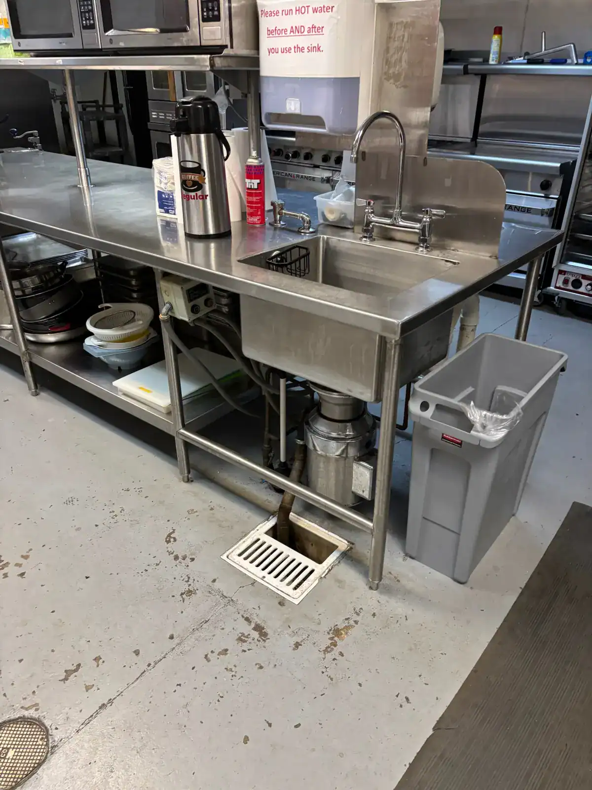 Older gray church kitchen floor with wear around sinks and floor drains