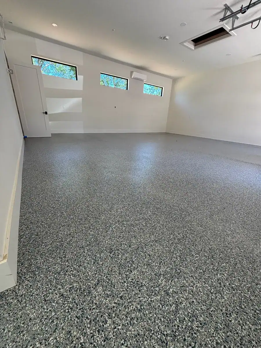 Finished custom gray full-broadcast flake floor across the main garage bay.