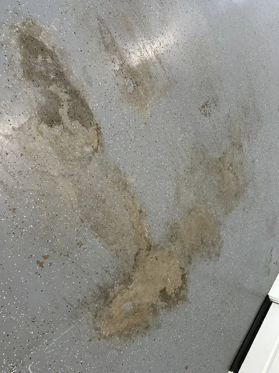 Close-up of severe delamination in an older DIY garage floor coating